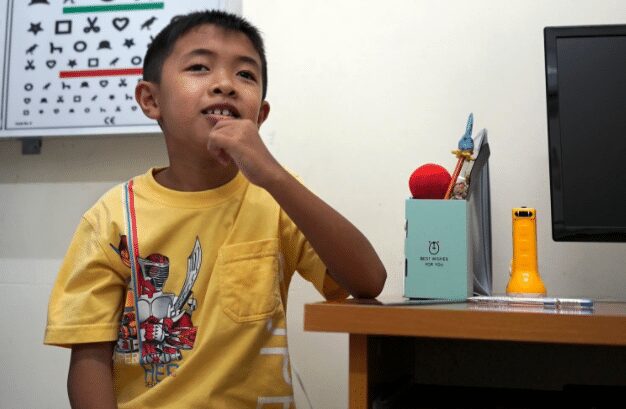 Clinician examines boy using slit lamp