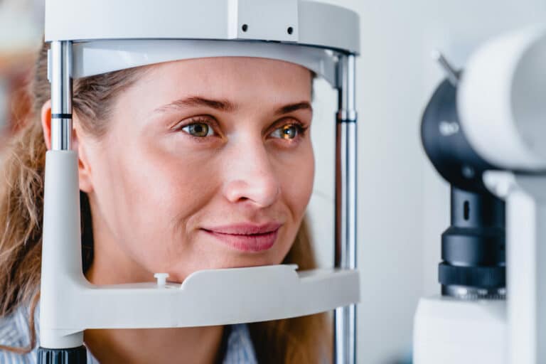 Cropped photo of cheerful smiling patient checking her vision with the help of ophthalmic tools