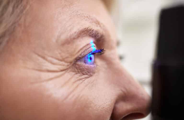 Eye exam, vision or laser test for an old woman with a machine at optometry consultation for retina.