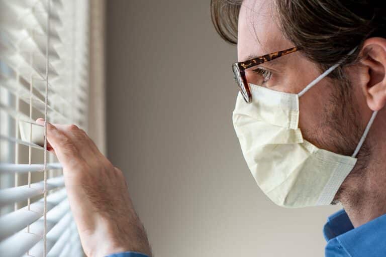 face mask man looking out window blinds