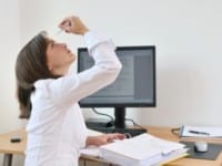 Woman using eye drops at computer work station