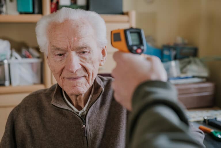 Nurse measures temperature of elderly man