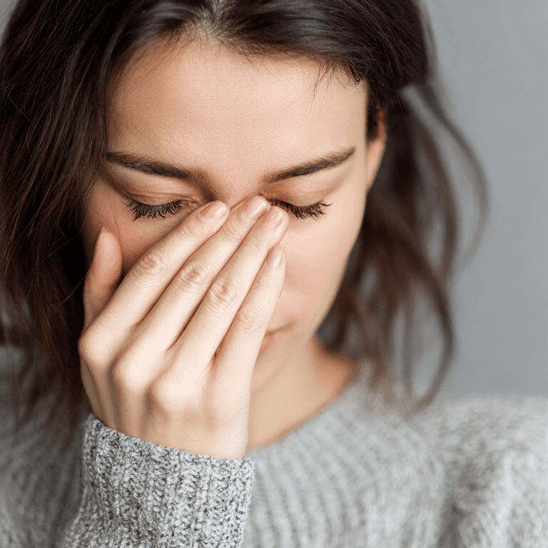 Woman with hand on face, eyes closed.